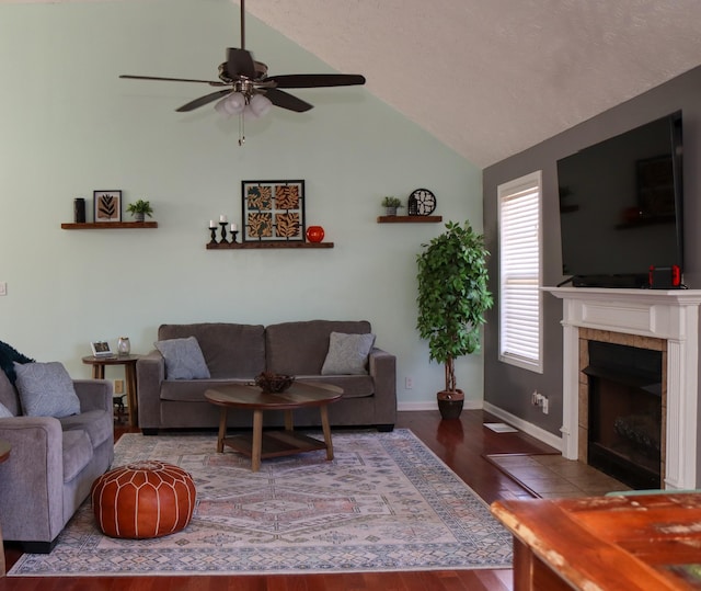 living room with lofted ceiling, hardwood / wood-style flooring, ceiling fan, and a tiled fireplace