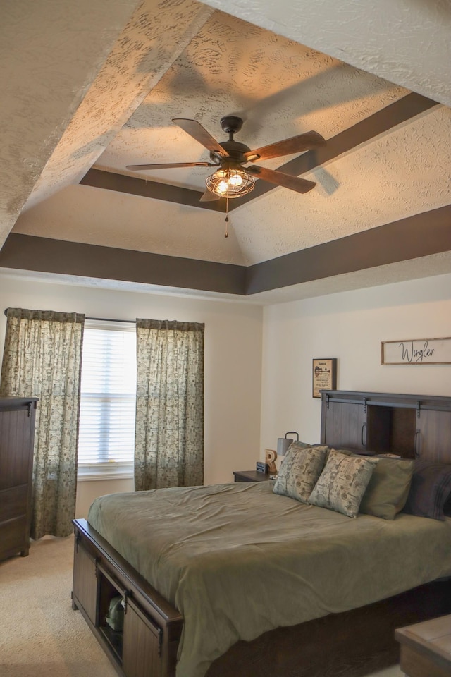 bedroom with light carpet, a tray ceiling, a textured ceiling, and ceiling fan