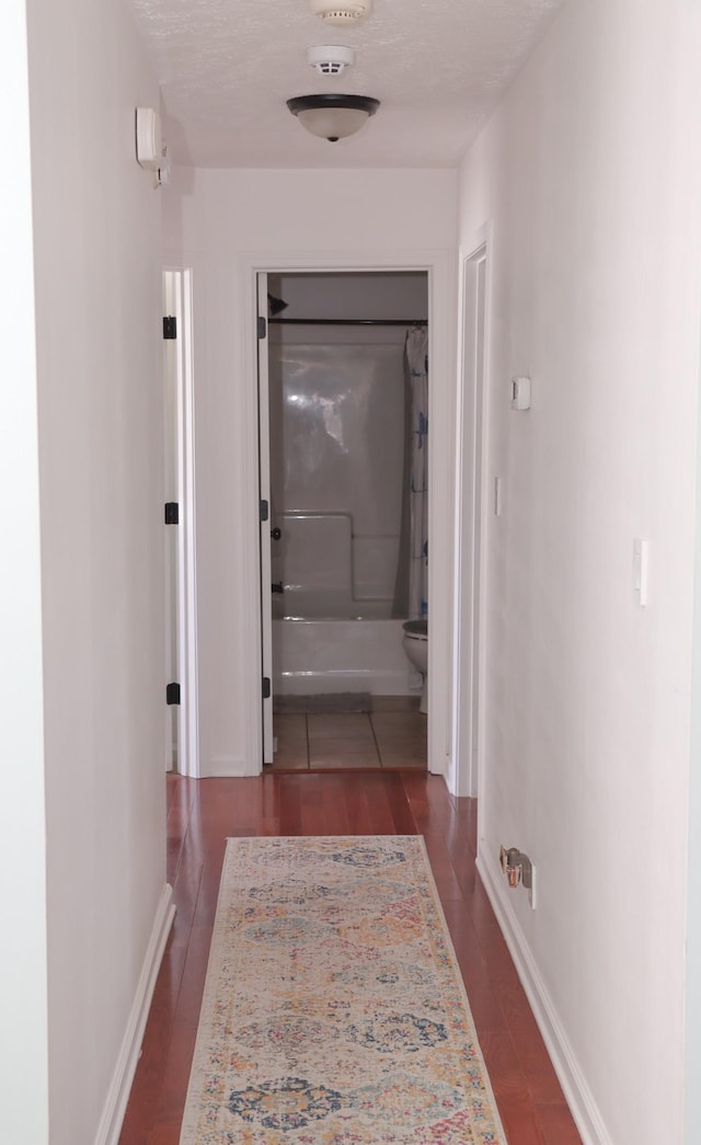 hall featuring a textured ceiling and dark hardwood / wood-style flooring