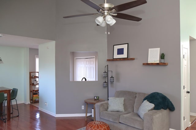 living room featuring dark hardwood / wood-style floors, ceiling fan, and a high ceiling