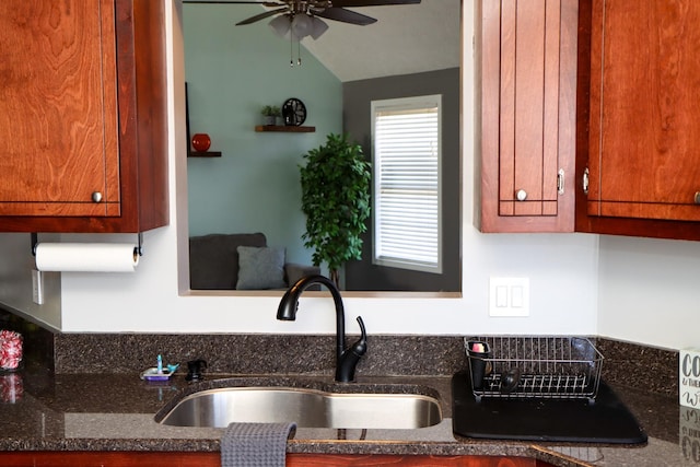 kitchen featuring dark stone countertops, sink, vaulted ceiling, and ceiling fan