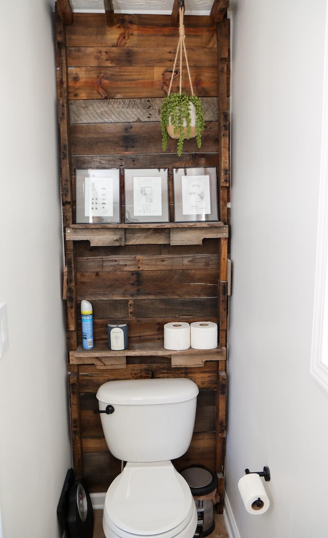 bathroom featuring toilet and wood walls