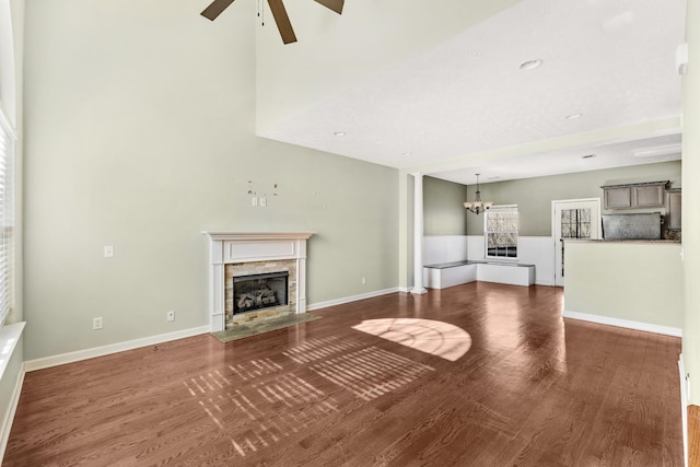 unfurnished living room featuring dark hardwood / wood-style flooring and ceiling fan with notable chandelier