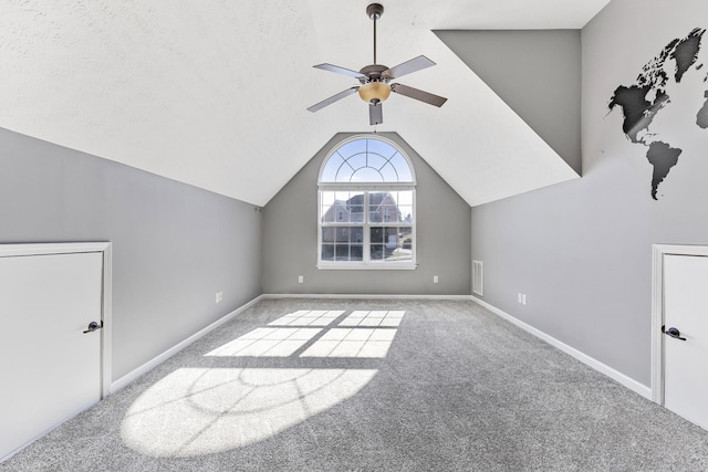 additional living space featuring ceiling fan, light colored carpet, lofted ceiling, and a textured ceiling