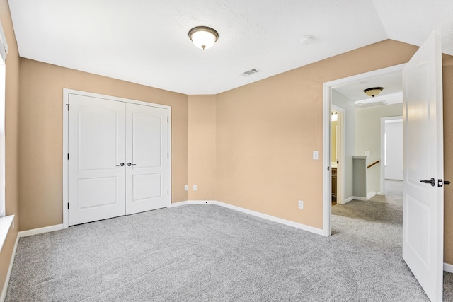 unfurnished bedroom featuring carpet, lofted ceiling, and a closet