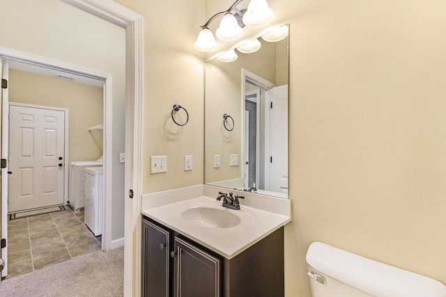 bathroom with vanity, washer and clothes dryer, and toilet