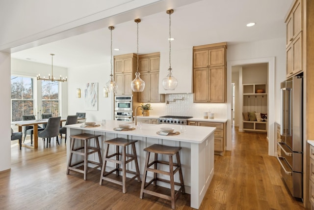 kitchen featuring appliances with stainless steel finishes, a kitchen island with sink, a kitchen breakfast bar, dark hardwood / wood-style floors, and tasteful backsplash