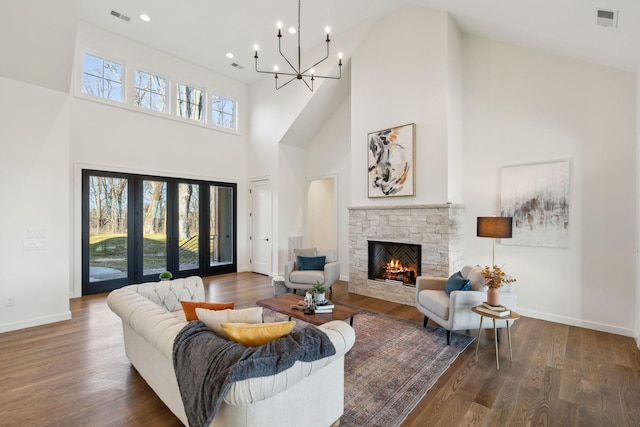 living room featuring a fireplace, dark hardwood / wood-style floors, a chandelier, and a high ceiling