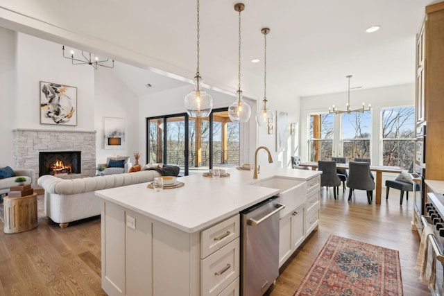 kitchen featuring vaulted ceiling with beams, pendant lighting, stainless steel appliances, a kitchen island with sink, and white cabinets