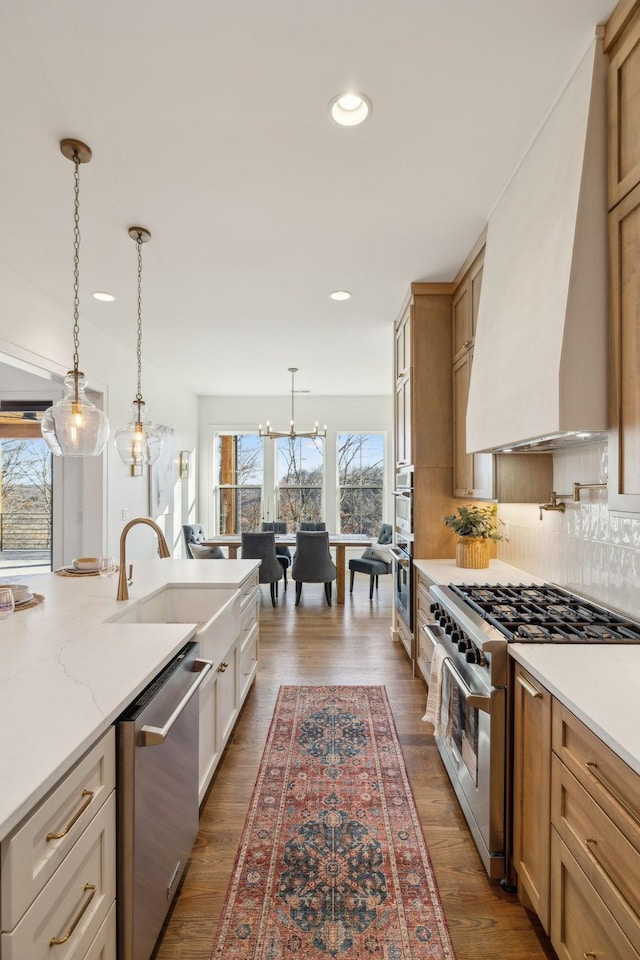 kitchen with pendant lighting, sink, appliances with stainless steel finishes, tasteful backsplash, and custom range hood