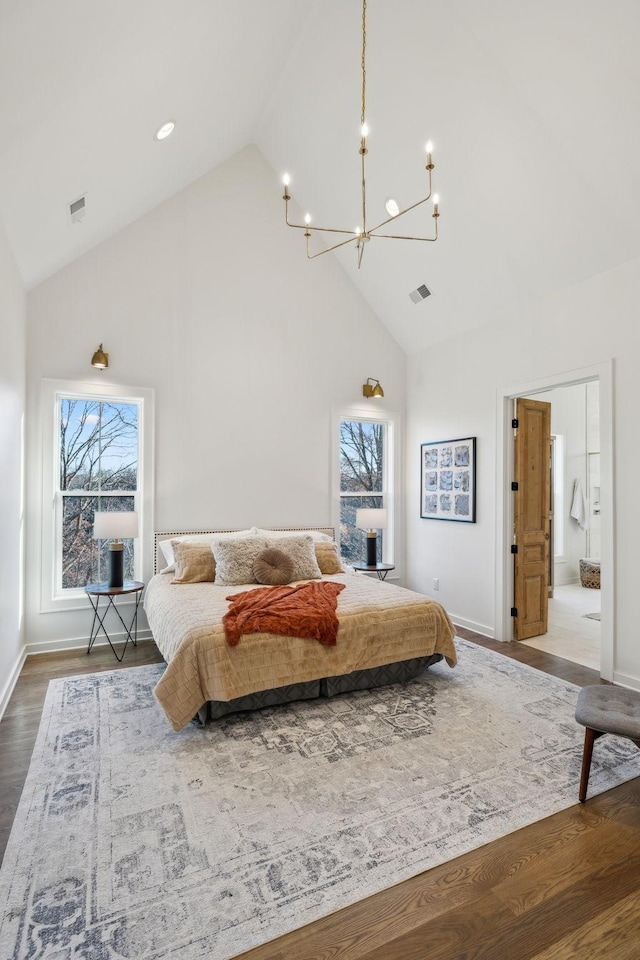 bedroom with hardwood / wood-style floors, high vaulted ceiling, a chandelier, and ensuite bathroom