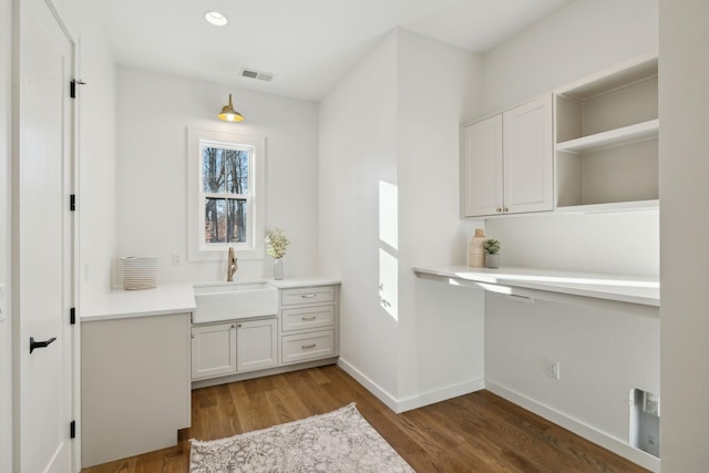 kitchen with hardwood / wood-style flooring, sink, and white cabinets