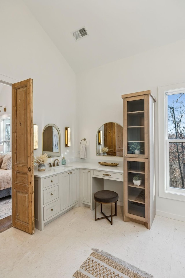 bathroom featuring a healthy amount of sunlight, high vaulted ceiling, and vanity