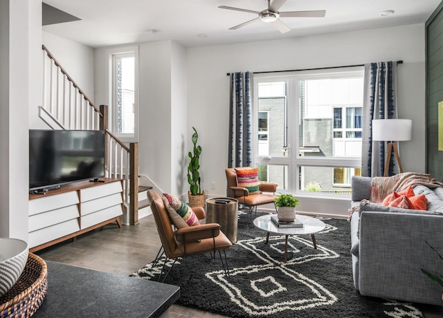 living room with dark wood-type flooring, ceiling fan, and a wealth of natural light