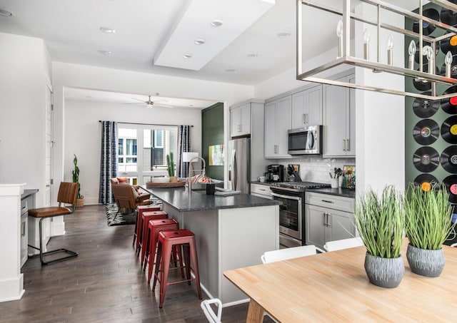 kitchen featuring dark wood-type flooring, sink, a center island with sink, appliances with stainless steel finishes, and gray cabinets