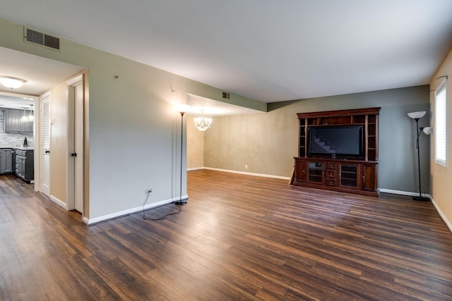 unfurnished living room featuring dark hardwood / wood-style flooring and a notable chandelier