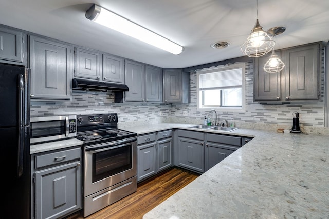 kitchen featuring sink, appliances with stainless steel finishes, dark hardwood / wood-style floors, light stone counters, and decorative light fixtures