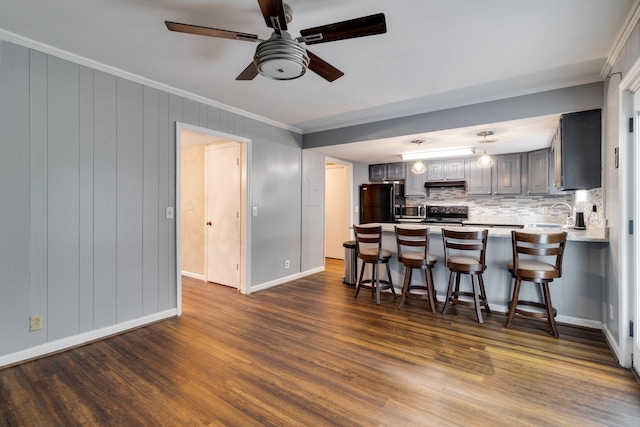 kitchen featuring a breakfast bar area, gray cabinetry, dark hardwood / wood-style floors, kitchen peninsula, and stainless steel appliances