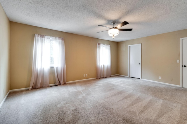 spare room with ceiling fan, light carpet, and a textured ceiling