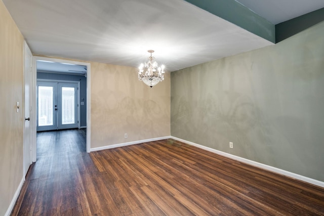 unfurnished room with dark wood-type flooring, a chandelier, and french doors