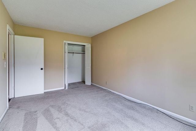 unfurnished bedroom with light colored carpet, a textured ceiling, and a closet