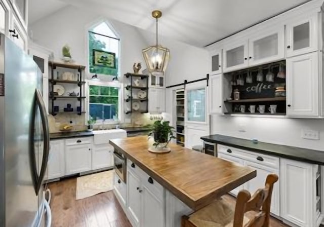 kitchen with white cabinetry, a barn door, stainless steel fridge, and decorative light fixtures