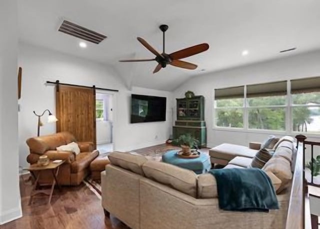 living room with a barn door, lofted ceiling, hardwood / wood-style flooring, and a wealth of natural light