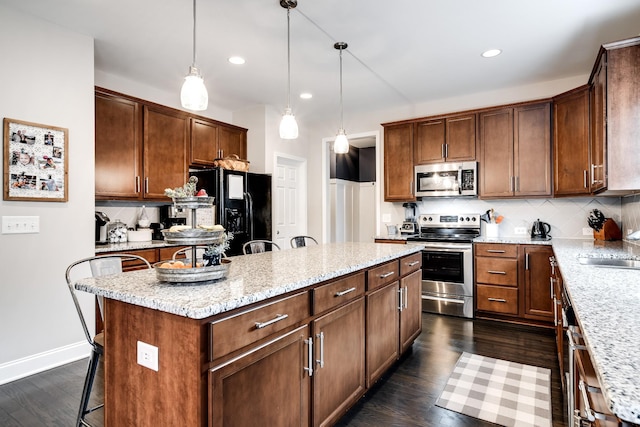 kitchen featuring tasteful backsplash, stainless steel appliances, a center island, and hanging light fixtures