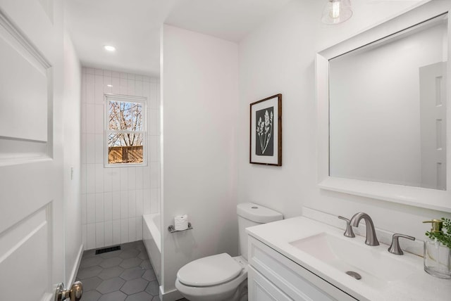 full bathroom with tile patterned flooring, vanity, tiled shower / bath, and toilet