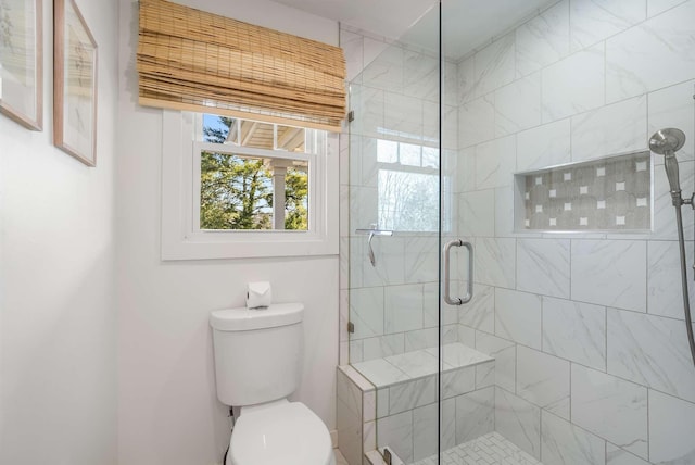 bathroom with a shower with shower door and toilet