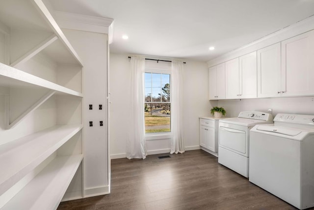 laundry room featuring dark wood-type flooring, cabinets, and washing machine and dryer