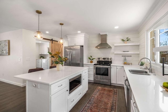 kitchen featuring appliances with stainless steel finishes, separate washer and dryer, hanging light fixtures, a barn door, and wall chimney range hood