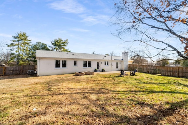 rear view of property with cooling unit and a yard