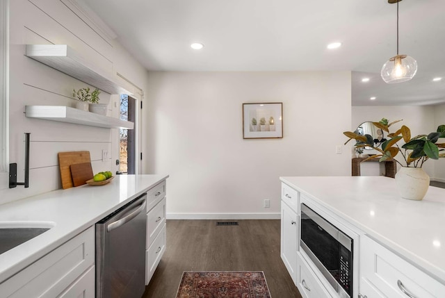 kitchen with hanging light fixtures, white cabinetry, appliances with stainless steel finishes, and dark hardwood / wood-style flooring