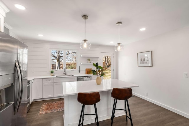 kitchen with sink, white cabinetry, a kitchen island, pendant lighting, and stainless steel appliances