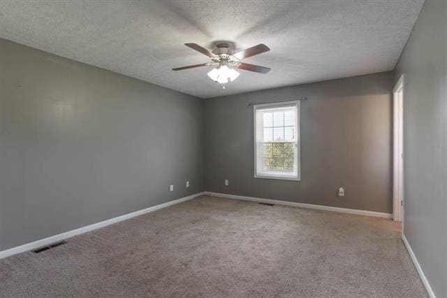 unfurnished room featuring ceiling fan, light colored carpet, and a textured ceiling