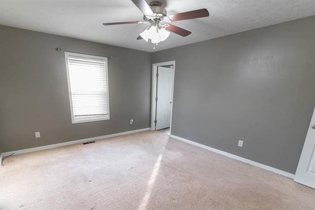 carpeted spare room featuring ceiling fan