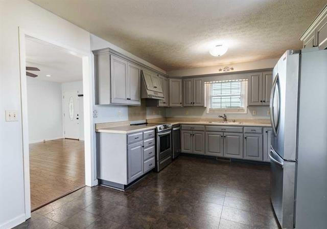 kitchen featuring sink, premium range hood, gray cabinetry, appliances with stainless steel finishes, and a textured ceiling