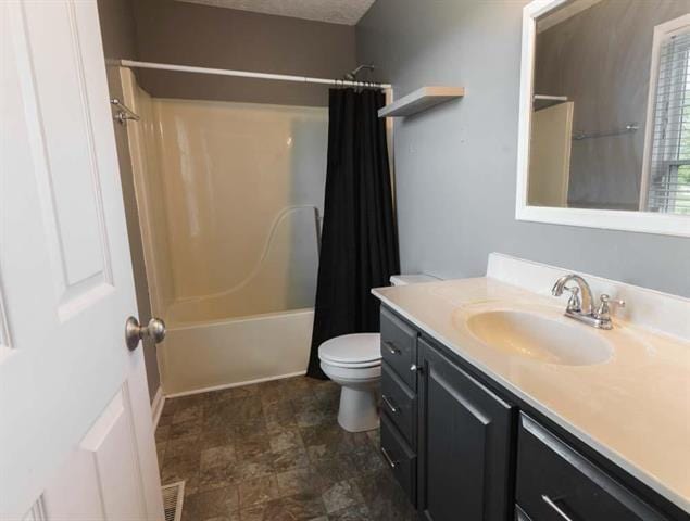 full bathroom featuring vanity, toilet, shower / bath combo with shower curtain, and a textured ceiling