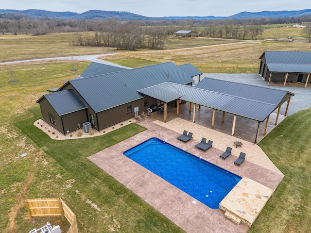 view of swimming pool featuring a rural view, a mountain view, an outbuilding, and a yard