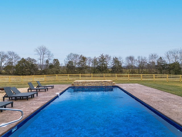 view of pool with a patio, a yard, and a rural view