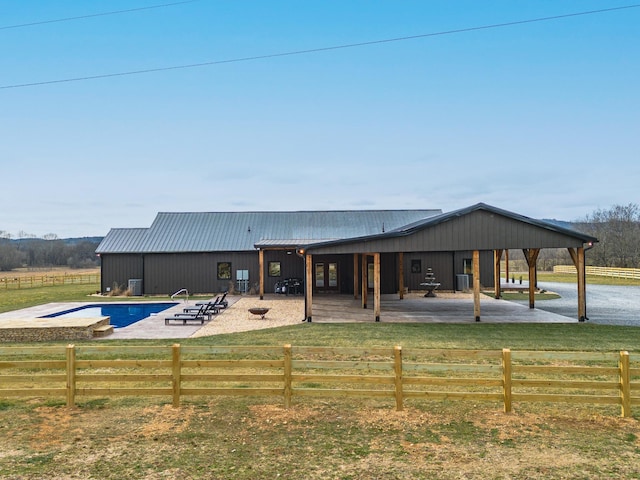 rear view of property with cooling unit, a fenced in pool, a patio, and a rural view