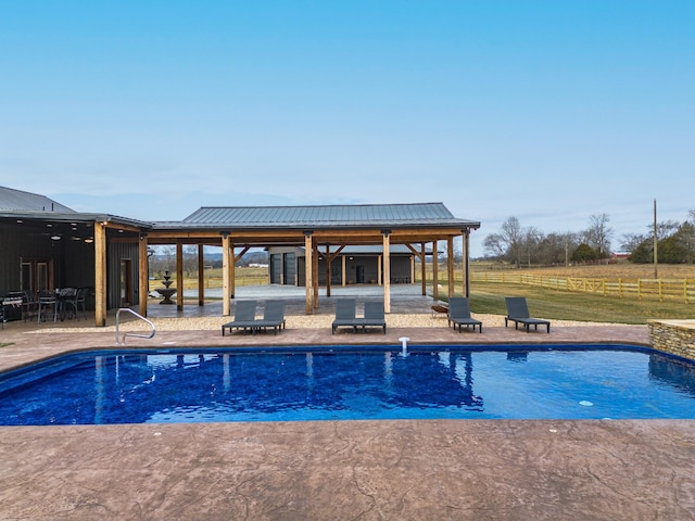 view of pool with a patio and a rural view