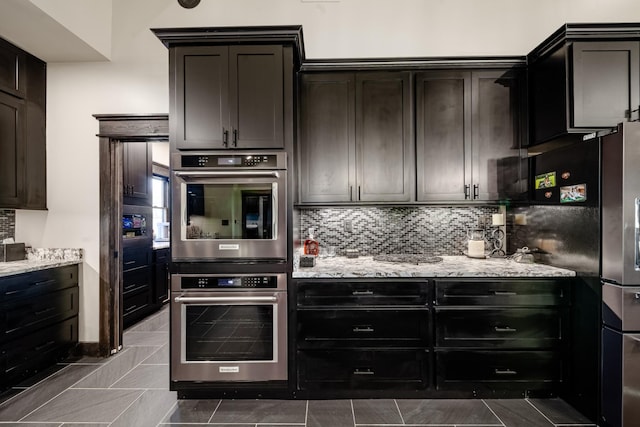 kitchen with backsplash, tile patterned flooring, fridge, light stone counters, and stainless steel double oven