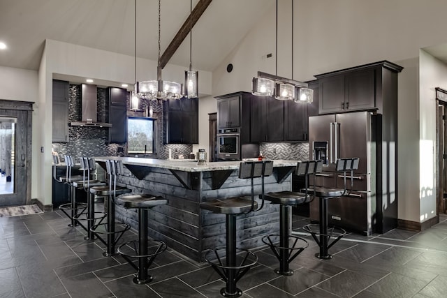 kitchen with dark brown cabinetry, wall chimney exhaust hood, decorative light fixtures, and appliances with stainless steel finishes