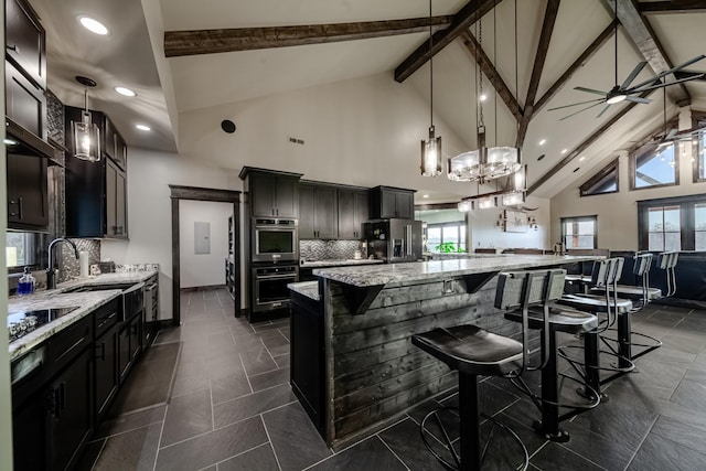 kitchen with sink, appliances with stainless steel finishes, a kitchen breakfast bar, pendant lighting, and a large island