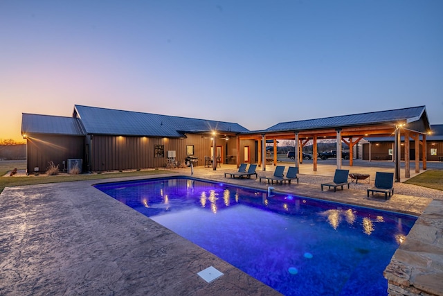 pool at dusk featuring a patio