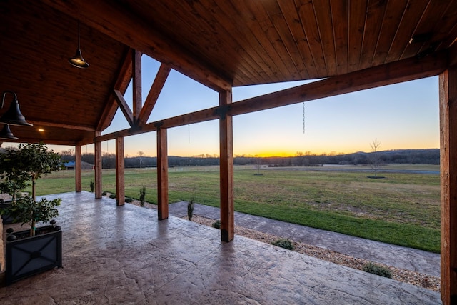 patio terrace at dusk featuring a rural view and a lawn