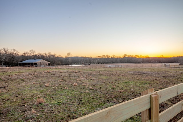 yard at dusk featuring a rural view