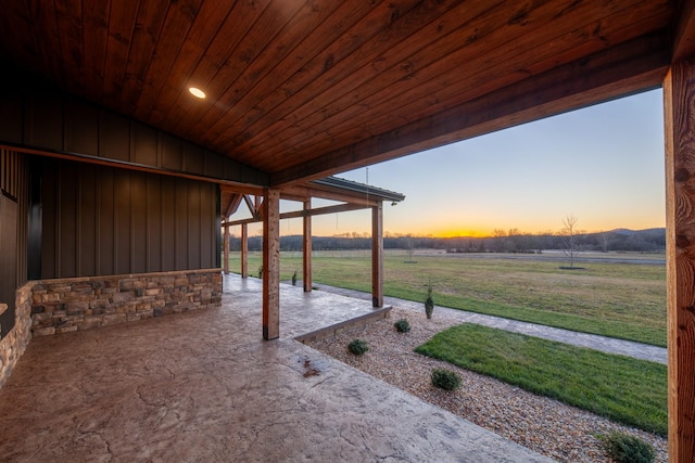 patio terrace at dusk featuring a rural view and a lawn